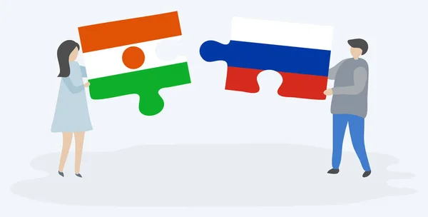 Dvojice Drží Dvě Skládanky Nigerienem Ruskými Vlajkami Národní Symboly Niger — Stockový vektor