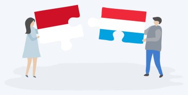 Monegasque ve Lüksemburg bayrakları ile iki bulmaca parçaları tutan çift. Monako ve Lüksemburg ulusal sembolleri birlikte.