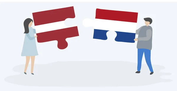 Para Trzyma Dwa Kawałki Puzzli Łotewskim Holenderskim Flag Symbole Narodowe — Wektor stockowy