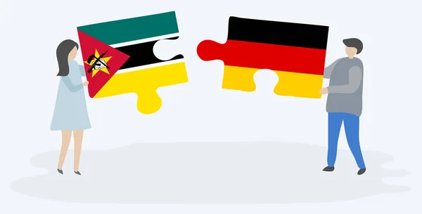 モザンビークとドイツの旗を持つ2つのパズルピースを保持しているカップル モザンビークとドイツの国のシンボル — ストックベクタ