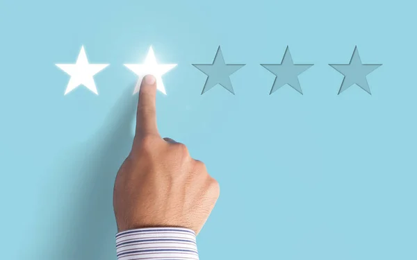 Hand choosing 2 stars rating on blue background