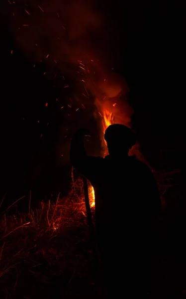 Man met de stok silhouet droog gras nachts branden — Stockfoto