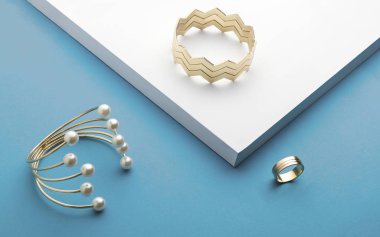 Zigzag bilezik ve inci altın bilezik altın bilezik ve beyaz ve mavi arka plan - altın yüzük