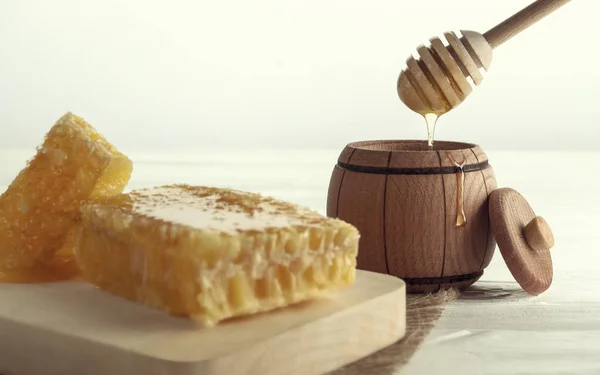 Honey dripping on wooden jar - Honey dipper in Wooden jar and honey comb on wooden tray