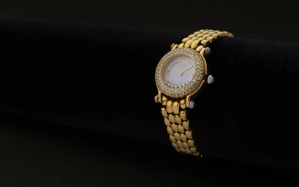 Golden women wrist watch with precious stones on dark background