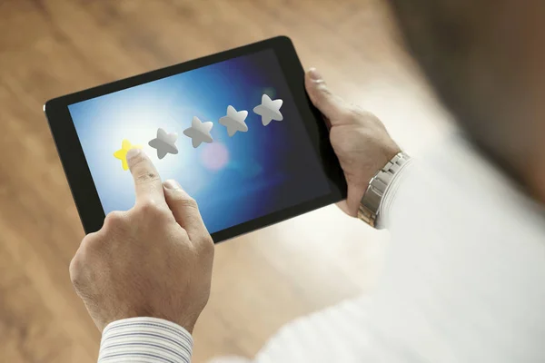 Mann wählt 1 Stern auf Tablet aus - negatives Feedback auf Gerätemonitor — Stockfoto