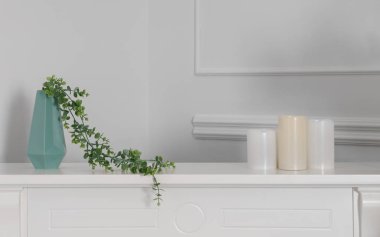 Beyaz tezgahüzerinde üç mum ile yeşil modern vazo