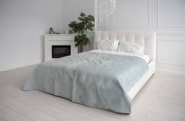 Side view of white leather bed with blue bedsheet and fireplace clipart