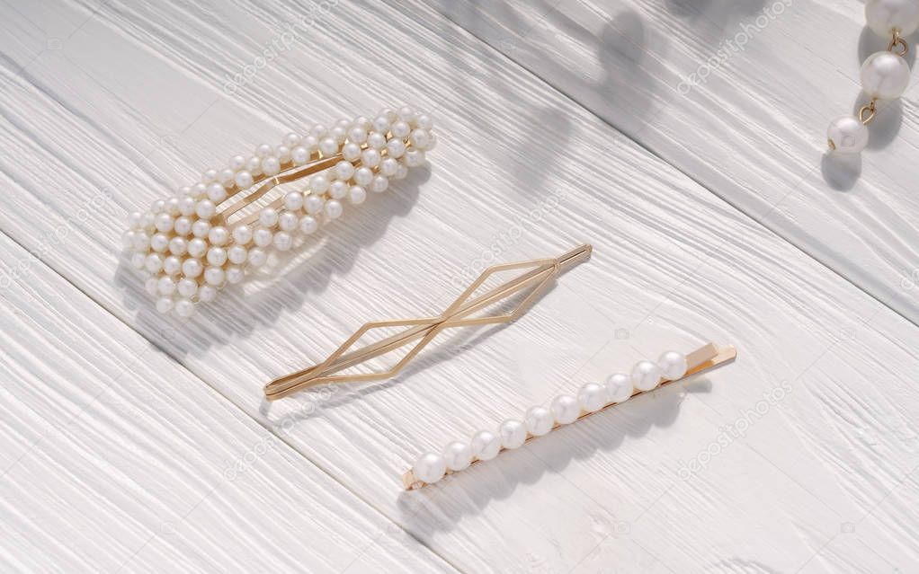 Golden and pearl hairpins on wooden background