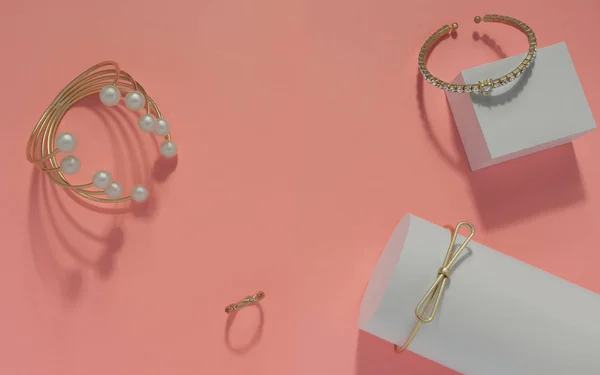 Bracelets dorés et perle sertis sur fond rose vue de dessus — Photo