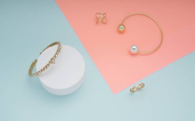 Pembe ve yeşil arka planda altın bilezik ve yüzük üst görünümü