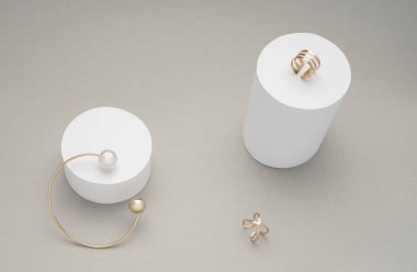 Beyaz silindirler üzerinde altın yüzük ile altın inci bilezik