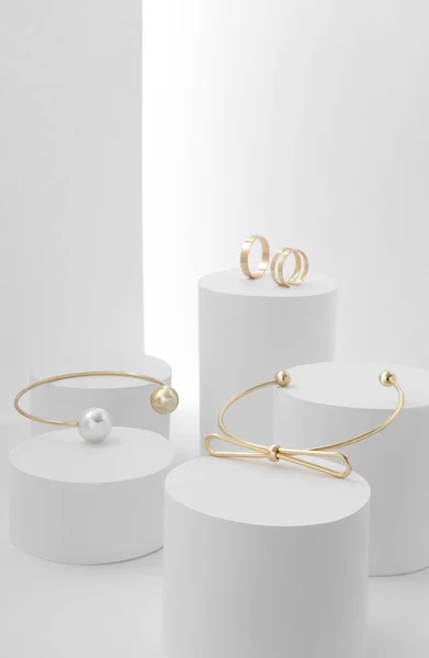 Золотые браслеты и кольца на белых цилиндрах — стоковое фото