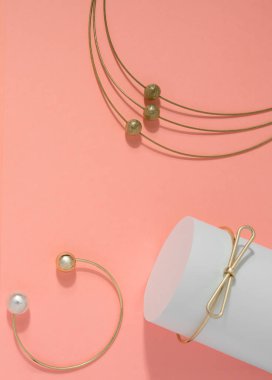 Altın kolye ve bilezik üst görünümü pembe arka plan üzerine ayarlanmış