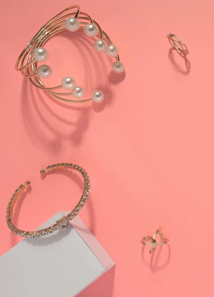 Vue du dessus des bracelets et bagues dorées sur fond rose — Photo