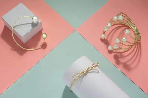 Oro con pulseras de perlas engastadas sobre papel rosa y fondo verde — Foto de Stock
