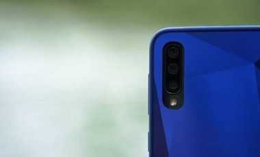 Bulanık arka plan kopyalama alanına sahip akıllı telefon arkası üçlü kamera