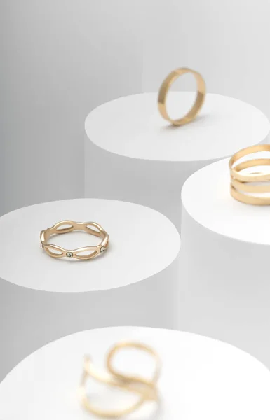 Nowoczesne złote pierścienie ustawione na białym cylindrze widok z góry — Zdjęcie stockowe