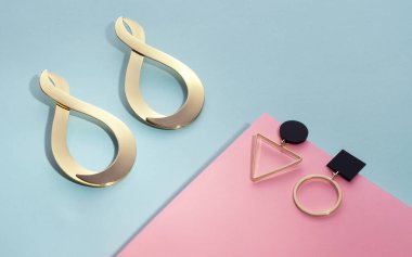 Mavi ve pembe arkaplanda Geometrik şekillerin üst görünümü altın küpeler