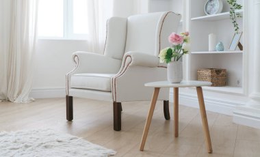 Deri beyaz koltuk ve çiçek vazosu olan modern ahşap masa.