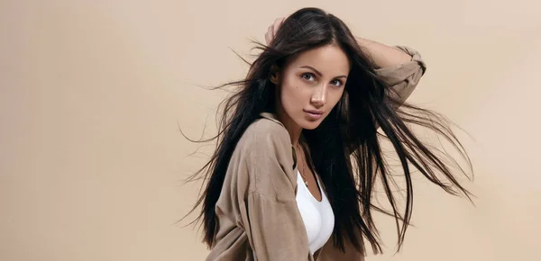 Retrato de menina morena bonita com cabelos longos saudáveis no fundo bege com espaço de cópia — Fotografia de Stock