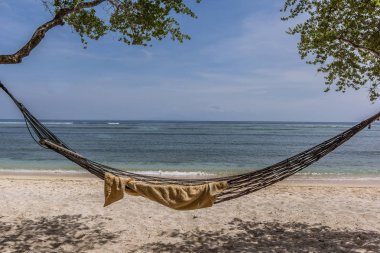 Gili Trawngan, tropikal denize yakın iki ağaç arasında sahilde 25 Nisan 2018 Endonezya, sallanan bir boş hamakta havlu