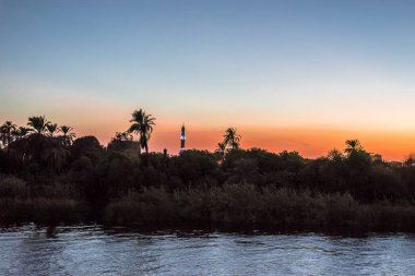 Gün batımı ve palms Nil Nehri'nin kıyısında, bir minare 26 Ekim 2018 su, Mısır, yansıtan