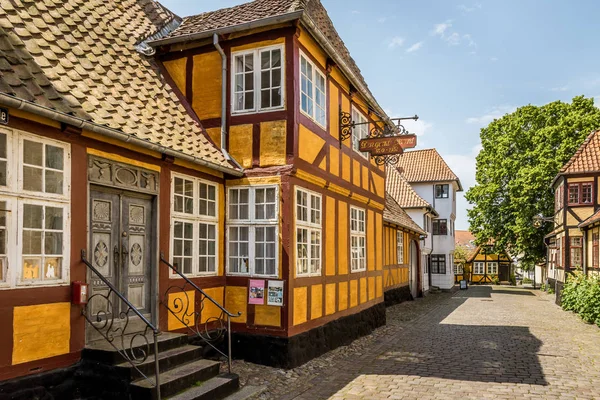 Une maison à colombages jaune avec deux étages dans une rue pavée — Photo