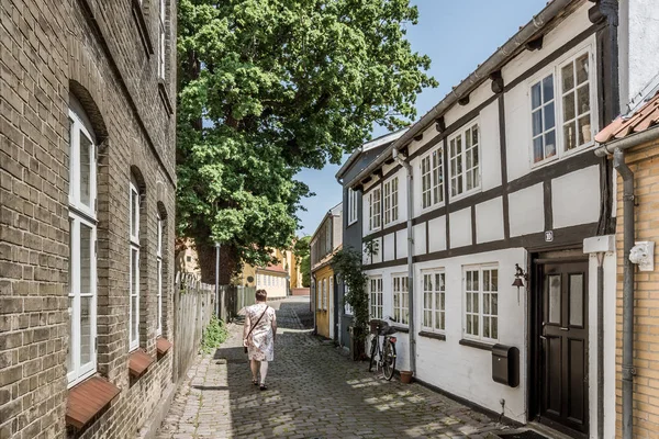 Frau geht eine schmale Gasse mit weißem Fachwerkhaus hinauf — Stockfoto