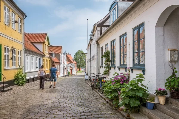 Hombre y mujer caminando a lo largo de un pintoresco carril con casas antiguas a —  Fotos de Stock