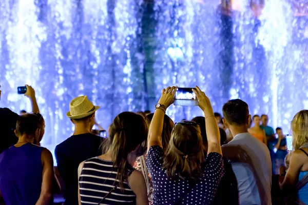 People shoot a smartphone fountain in the evening