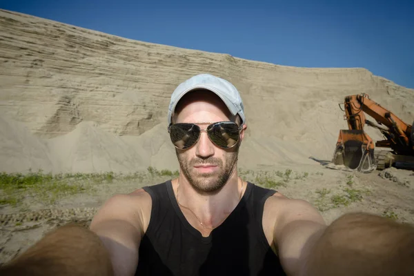 Selfies working on background excavator on sand quarry