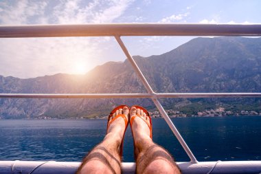 Kendi ayakları üzerinde korkuluk ile gemide dinlenme bir adam. Ayak üzerinde odaklanmak.