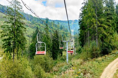Teleferik dağlarda. Kız dağın tepesinde bir bisiklet taşıyor.