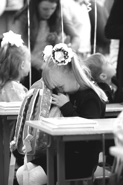 Девушка-первоклассница впервые в школе сидит за школьным столом — стоковое фото
