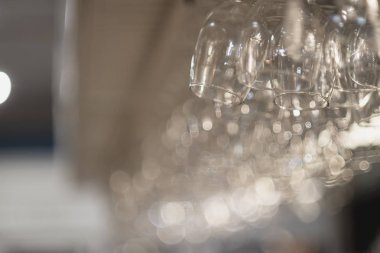 Bir sıra boş bardak bar tezgahının üzerinde asılı duruyor. Küçük alan derinliği