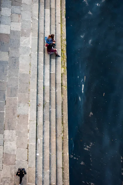 İki kız su kenarındaki setin merdivenlerinde oturuyorlar. Yukarıdan görüntüle — Stok fotoğraf