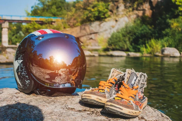 Helmet and sneakers on the river bank — Stock Photo, Image