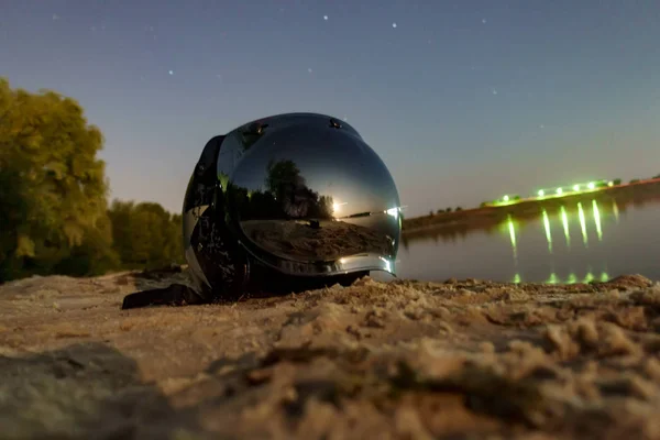 Motorcykel hjälm på flodbanken på natten — Stockfoto