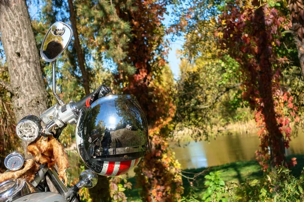 Casco colgado en el volante en el fondo del bosque de otoño y el río — Foto de Stock