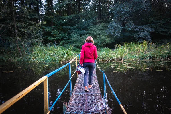 Дівчина з шоломом перетинає міст через річку — стокове фото