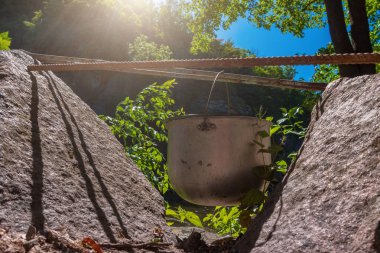 Turist pişirme potiki taş arasında asılı