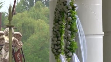 Düğün töreni için çiçek kemeri. Arka planda, yağmur yağıyor.