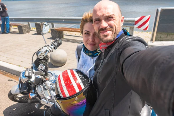 Un hombre con una mujer en cascos de motocicleta son fotografiados cerca de una motocicleta . —  Fotos de Stock