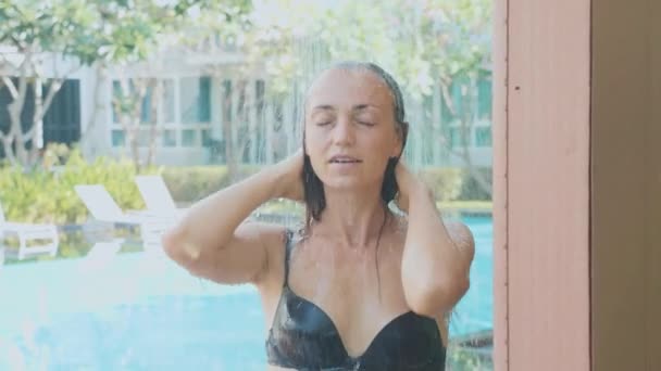 Yong красивая женщина принимает душ под открытым небом у бассейна в замедленной съемке — стоковое видео