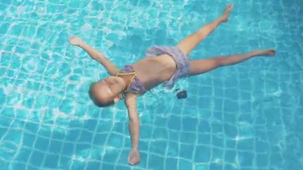 Malá roztomilá holka je plavání na zádech v bazénu v pomalém pohybu — Stock video