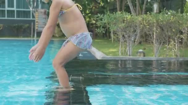 小さな女の子がスローモーションで屋外プールの水の中にダイブします。 — ストック動画