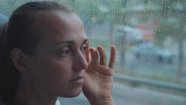 Προσωπογραφία νεαρής γυναίκας λυπημένος κοιτάζοντας έξω από το παράθυρο υγρό, ενώ ταξιδεύετε με λεωφορείο. — Αρχείο Βίντεο