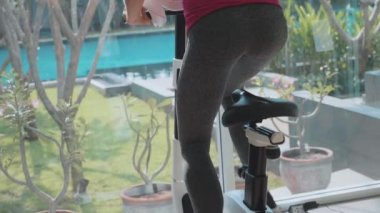 Yakın çekim kadın bacakları ve jimnastik salonu sabit bisiklet, ağır çekimde sürme eşek