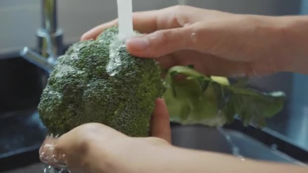 Крупным планом женские руки моют брокколи на домашней кухне в замедленной съемке — стоковое видео